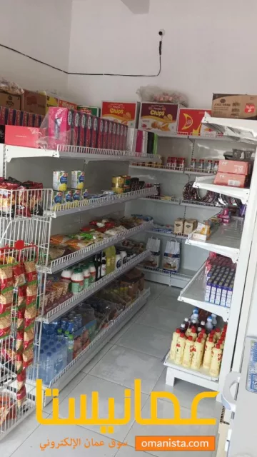 رفوف بقالة للبيع ولافته مضيئة في صحار