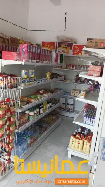 رفوف بقالة للبيع ولافته مضيئة في صحار